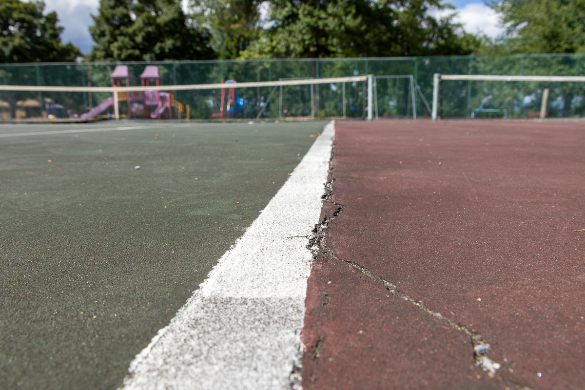 Close up view of smaller cracks on a damaged tennis court.