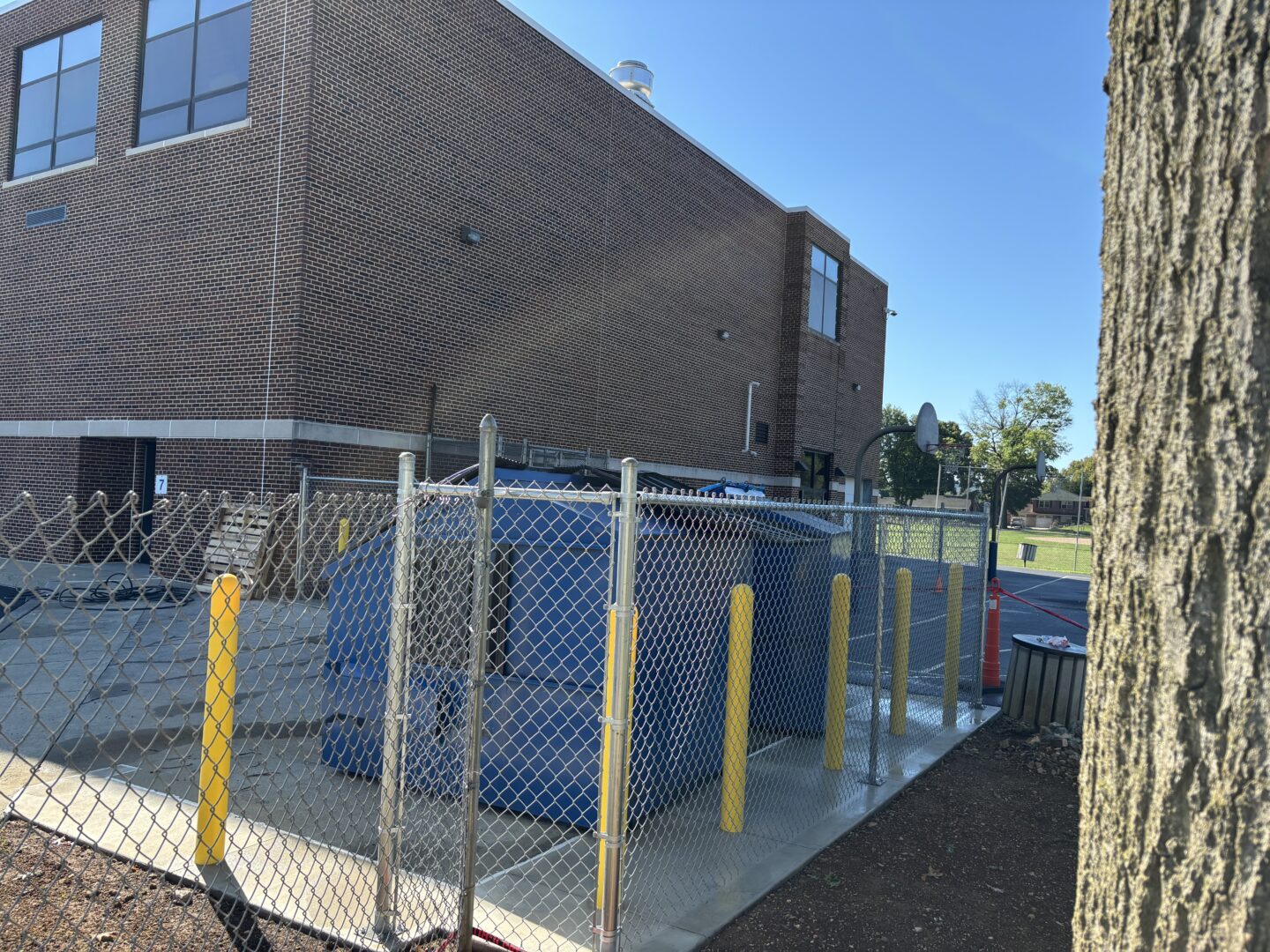 Back view of new chain-link fence around dumpster area.