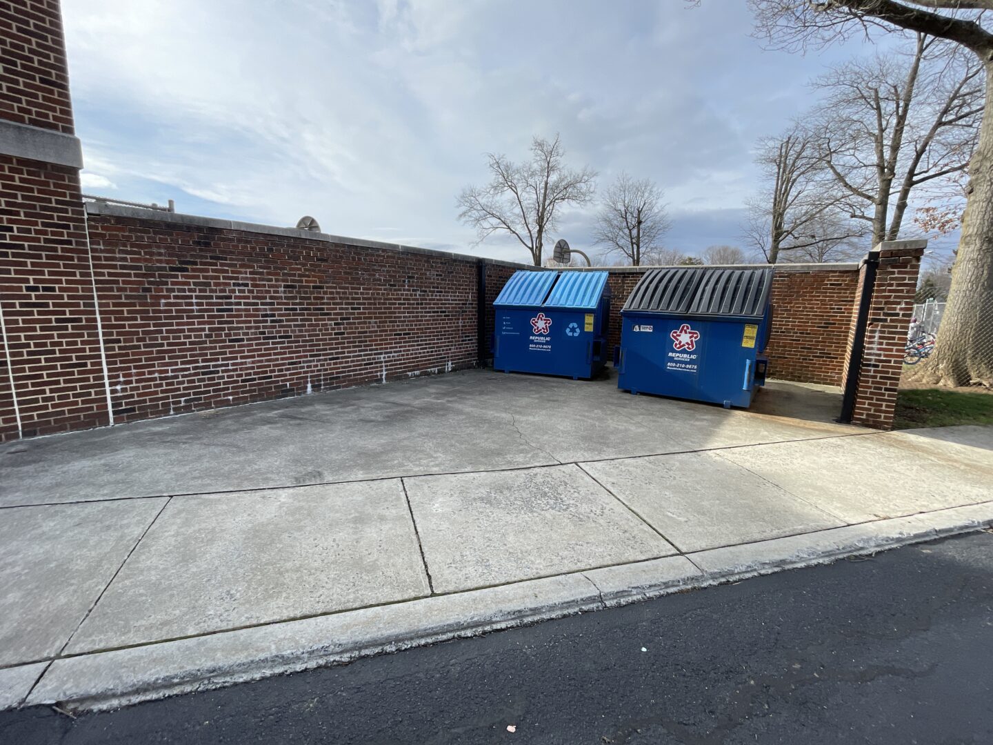 Damaged brick dumpster wall.